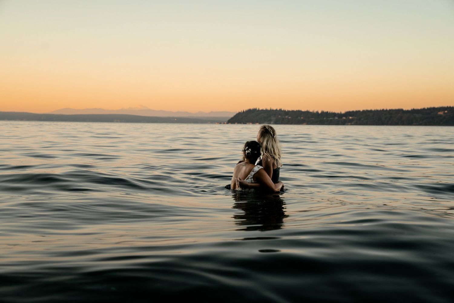 Silhouette of person in water during golden sunset at ocean beach.