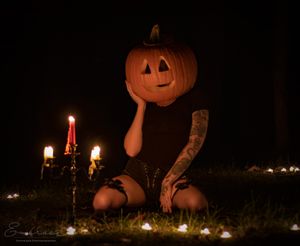 Halloween themed photo of illuminated jack o'lantern with candles in dark setting.