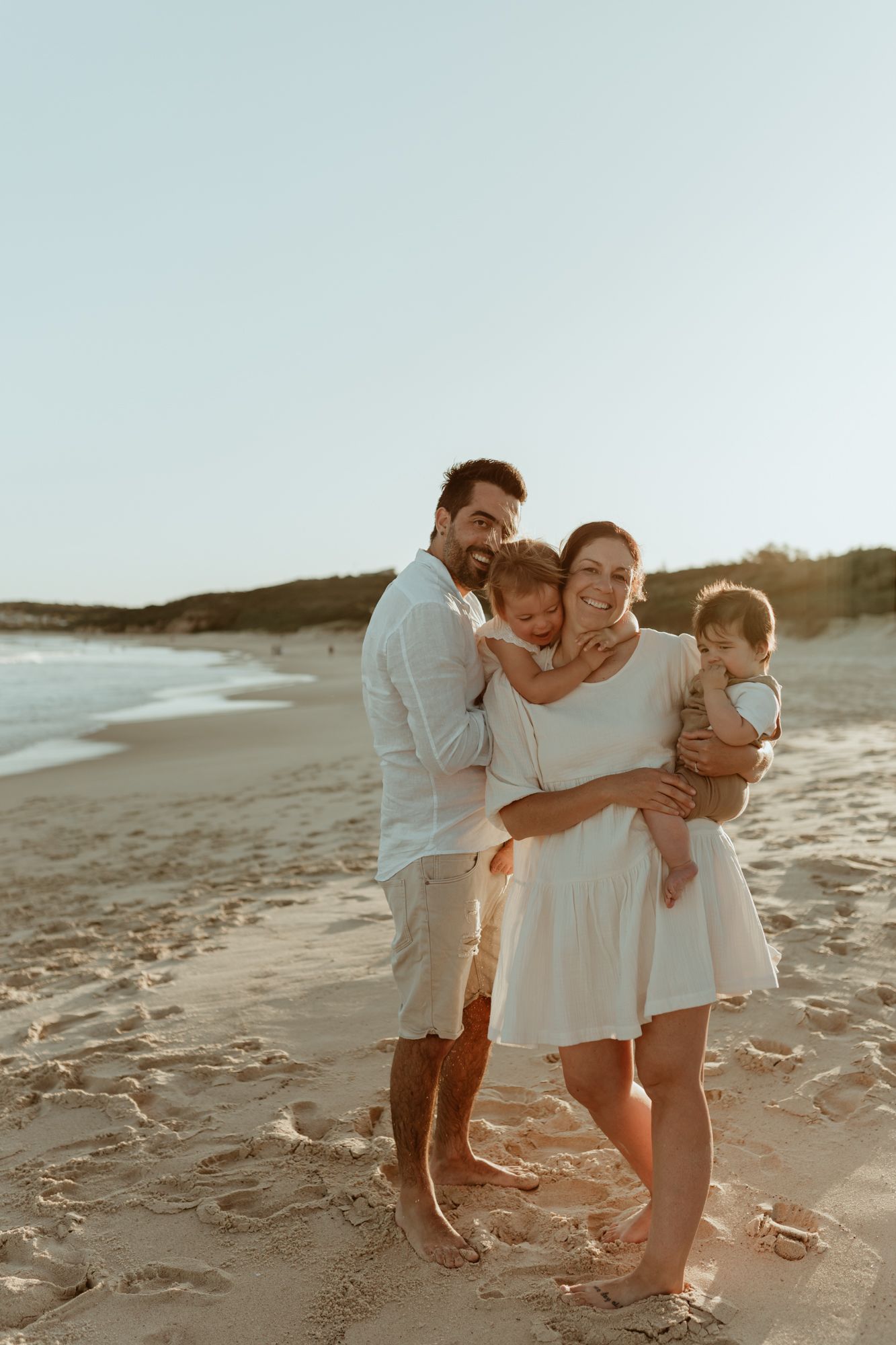 A happy family embracing together on a sandy beach at sunset.