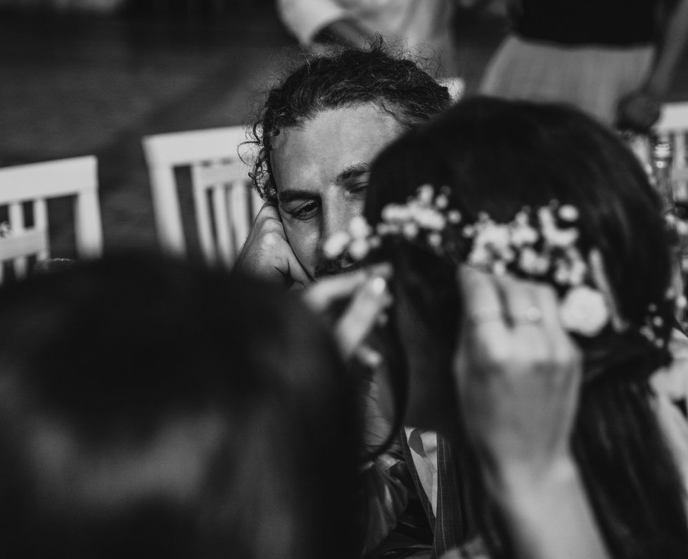 Black and white candid wedding photograph showing emotional moment during reception.