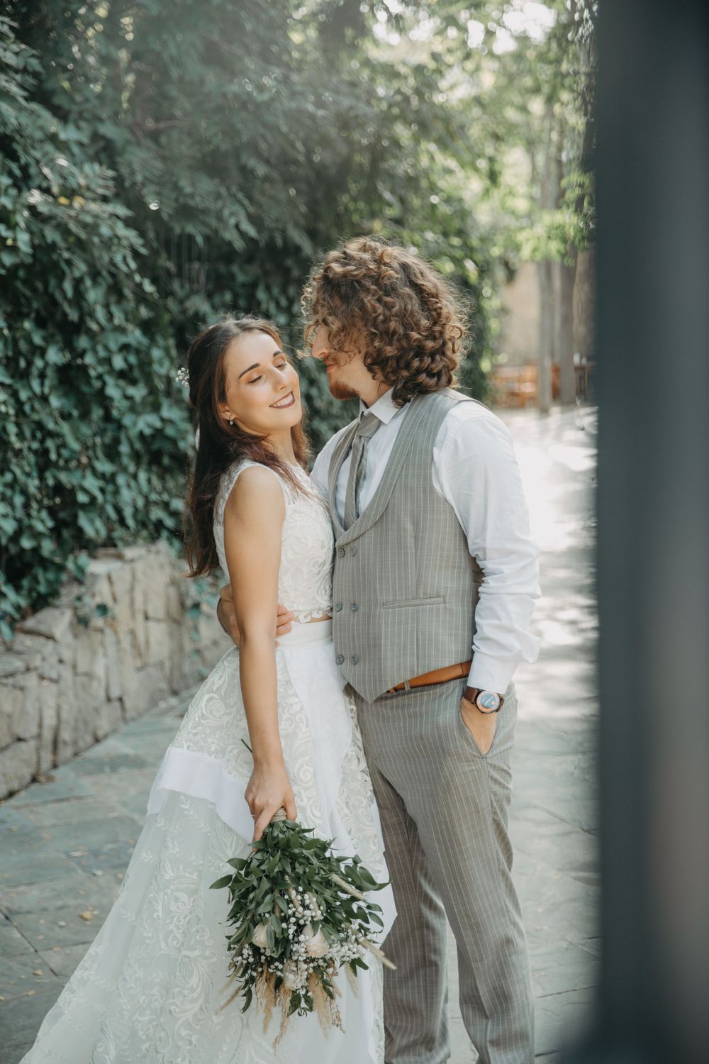 Happy couple sharing intimate moment against stone wall and greenery.