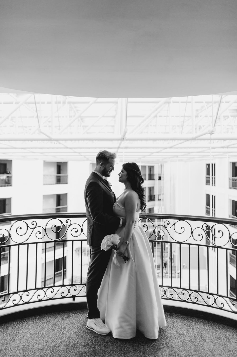 A romantic balcony moment with ornate railings and elegant wedding attire.