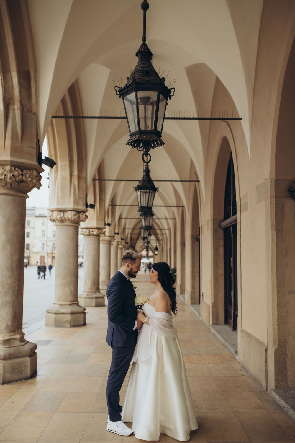 Wedding moment captured under ornate archways with vintage lanterns.