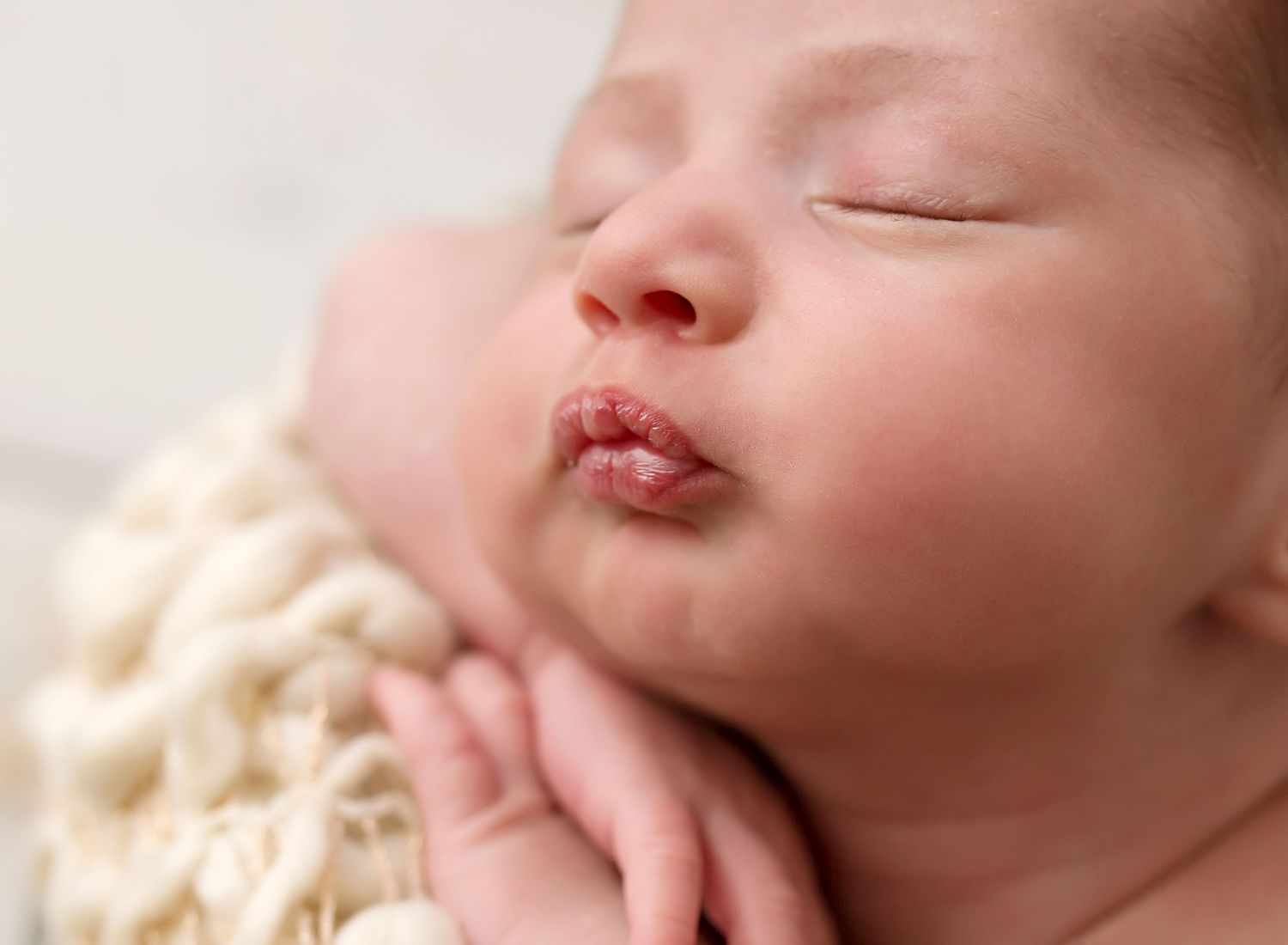 Close up of sleeping newborn's face with peaceful expression.