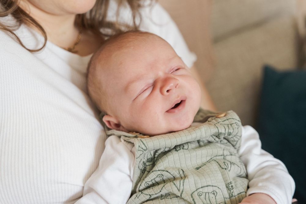 photograph of newborn baby being held against mothers chest