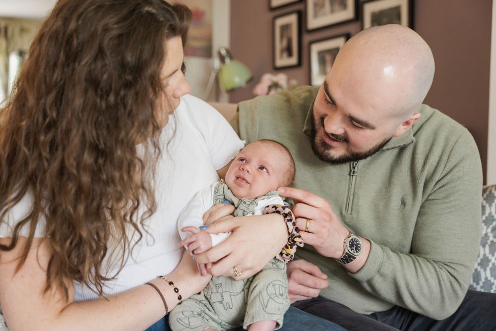 Image of mother and father looking at baby boy held in arms