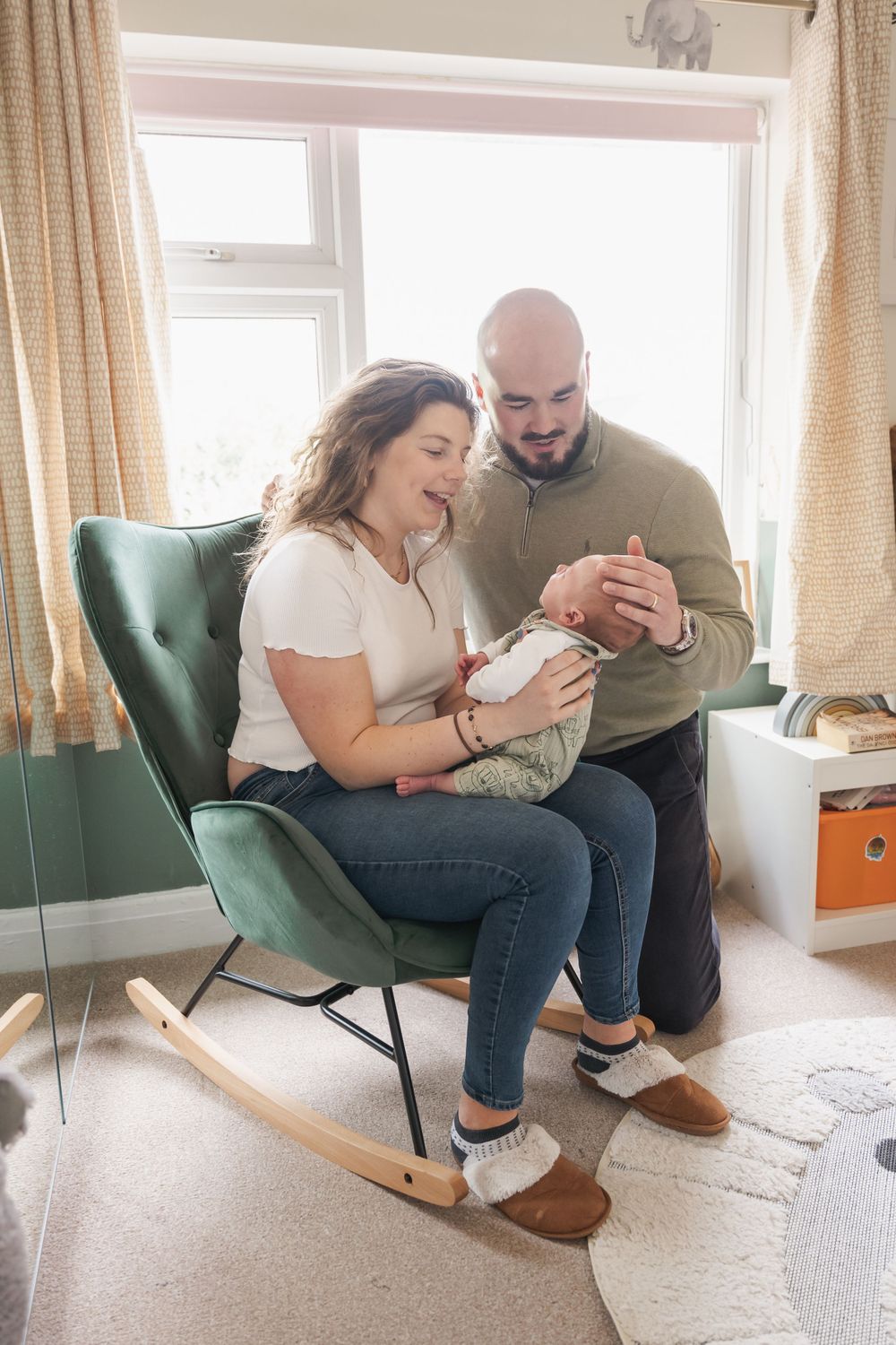 photograph of newborn baby being held on rocking chair in nursery
