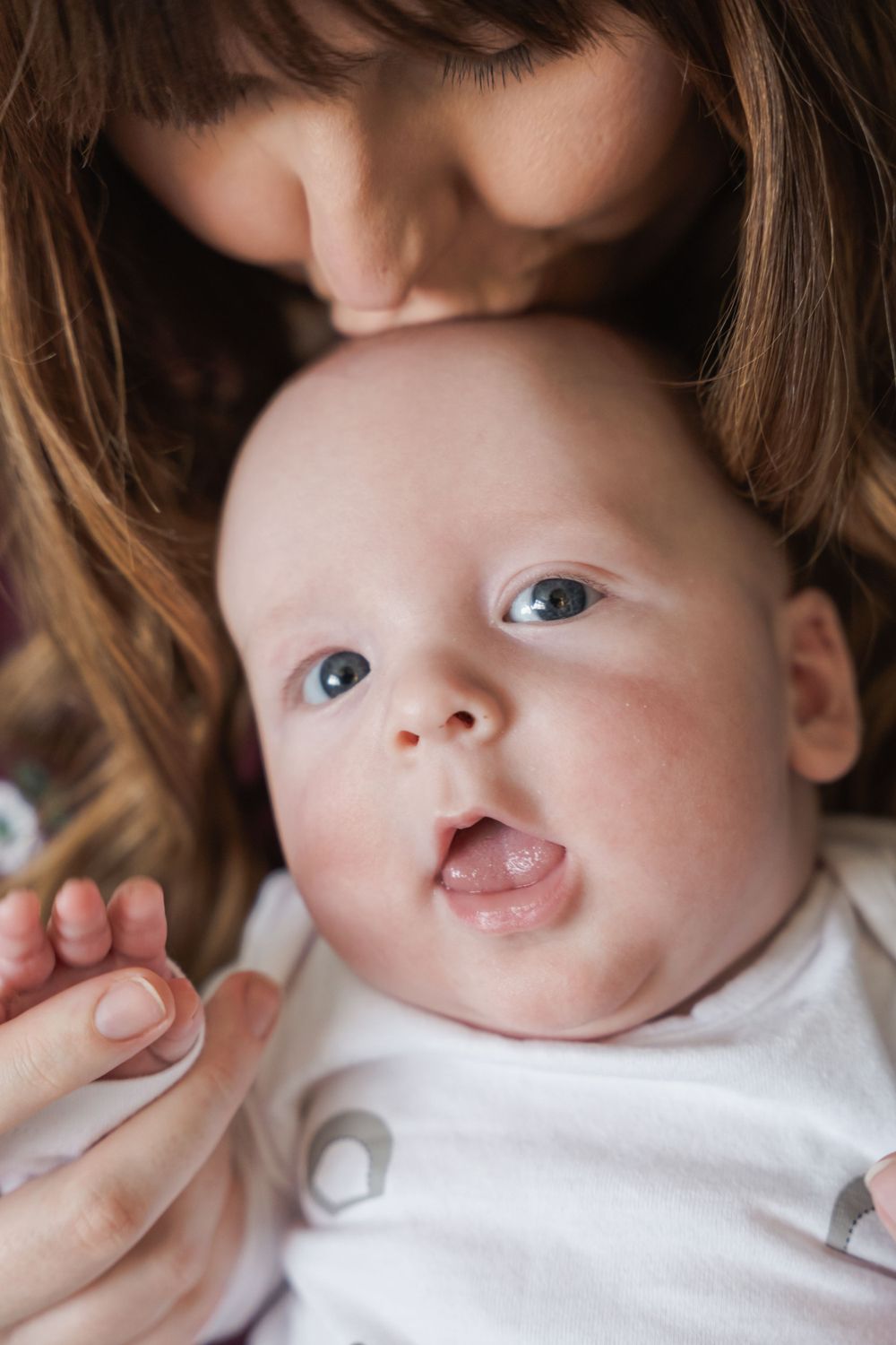 photograph of newborn boy being kissed by mother.