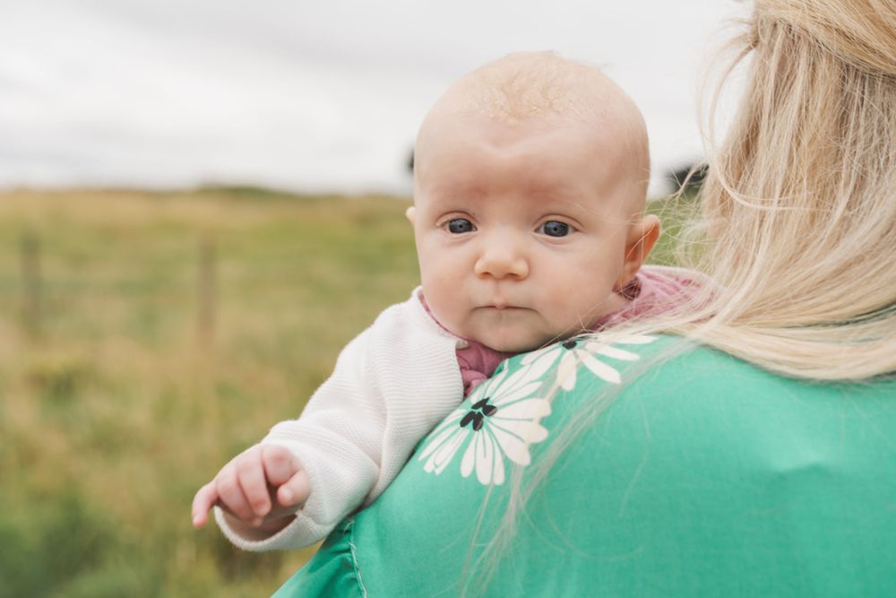 photograph of newborn baby being held over mother's shoulder