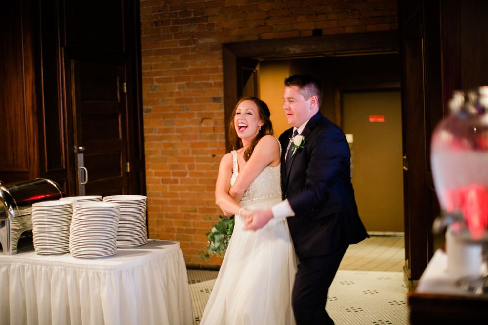 Laughing bride and groom make a grand entrance into their wedding reception venue together.