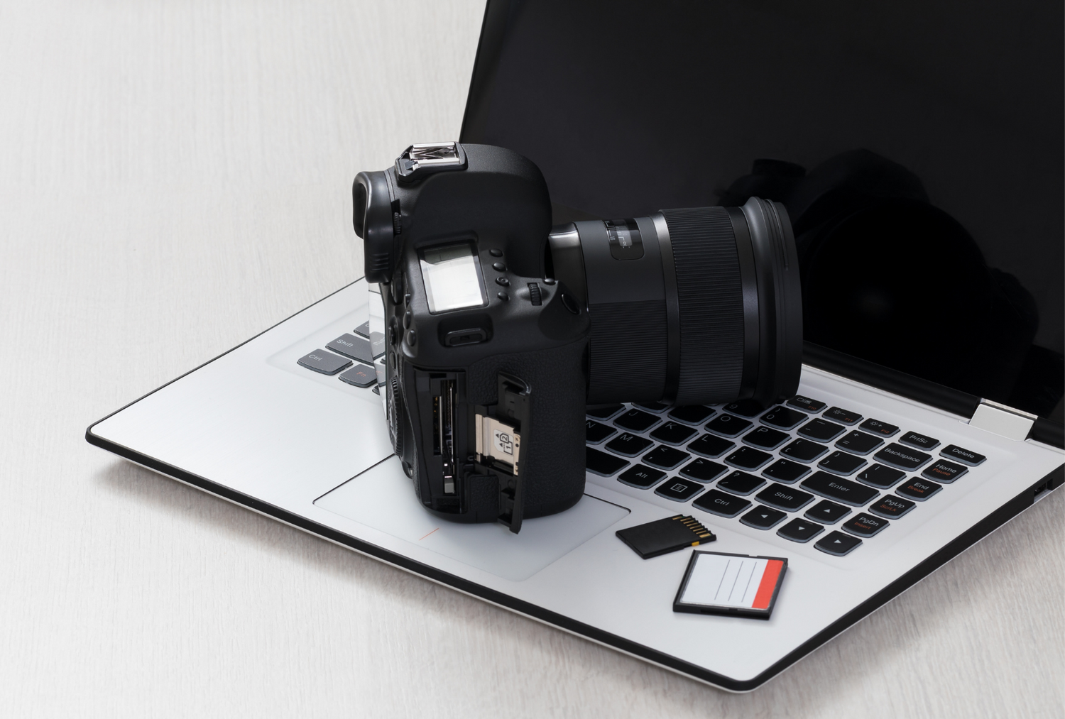 Close up photo of a MacBook, professional camera and memory cards