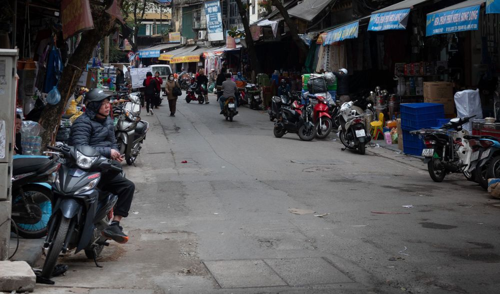 Urban alley with rows of parked motorcycles and storefronts on both sides.