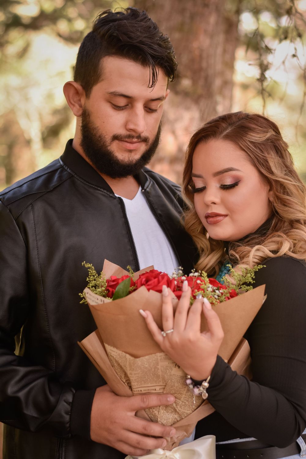 Couple admiring floral bouquet wrapped in kraft paper during outdoor photoshoot.