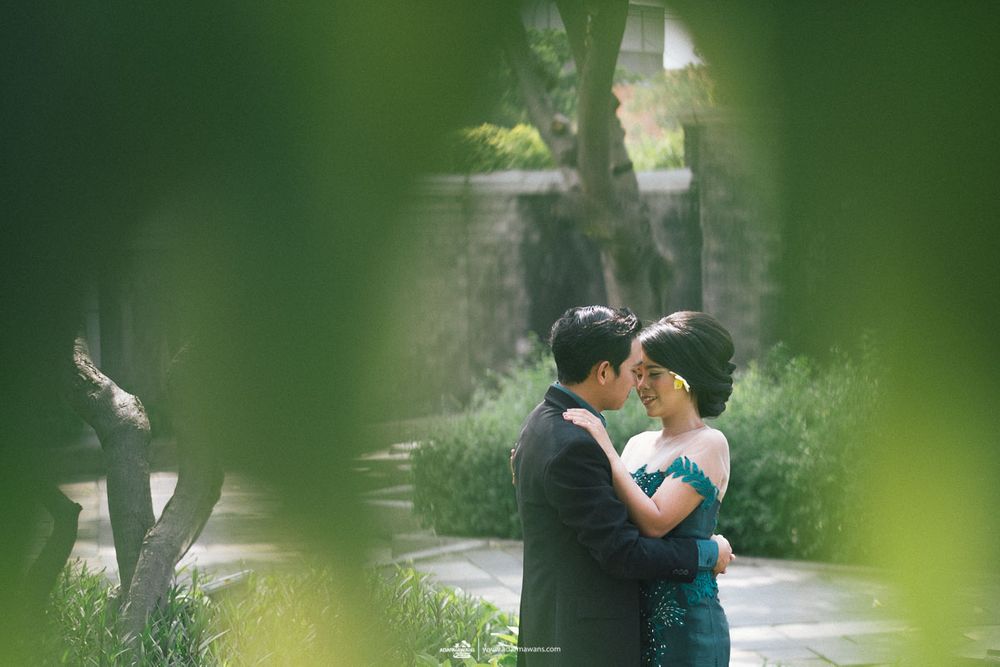 A couple sharing an intimate moment in a lush garden setting framed by greenery.