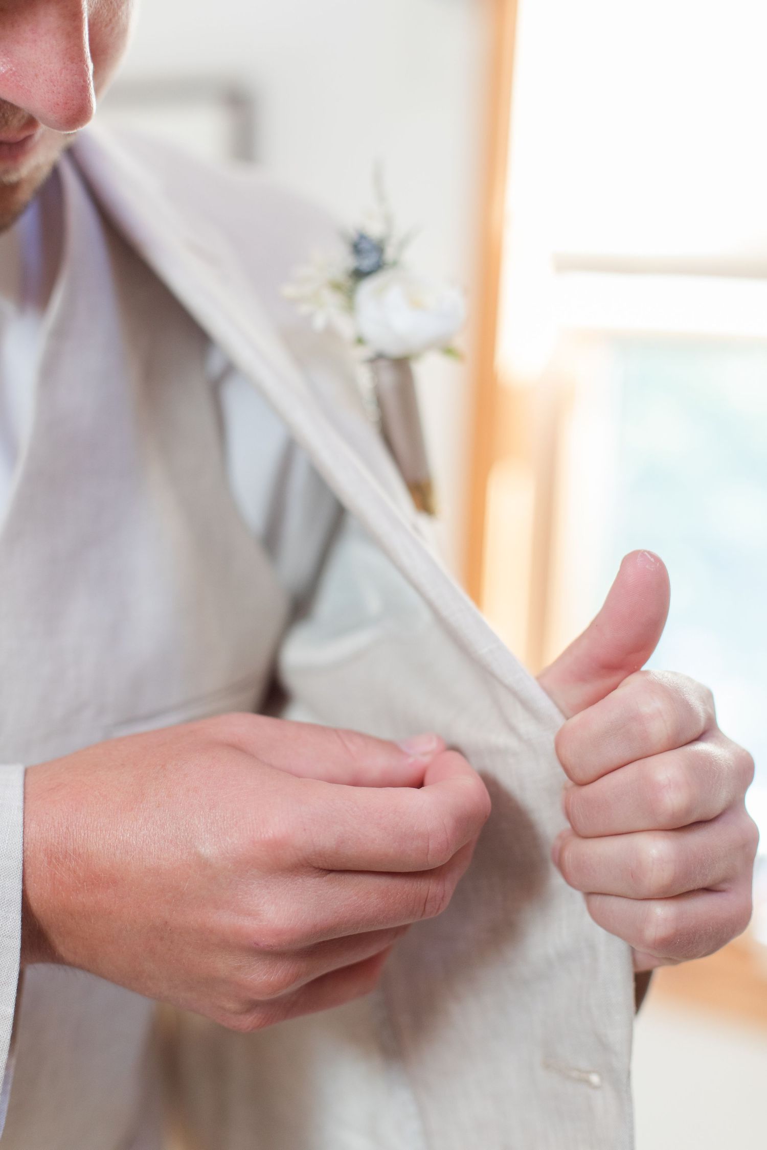 Close-up of hands adjusting white formal attire buttons.