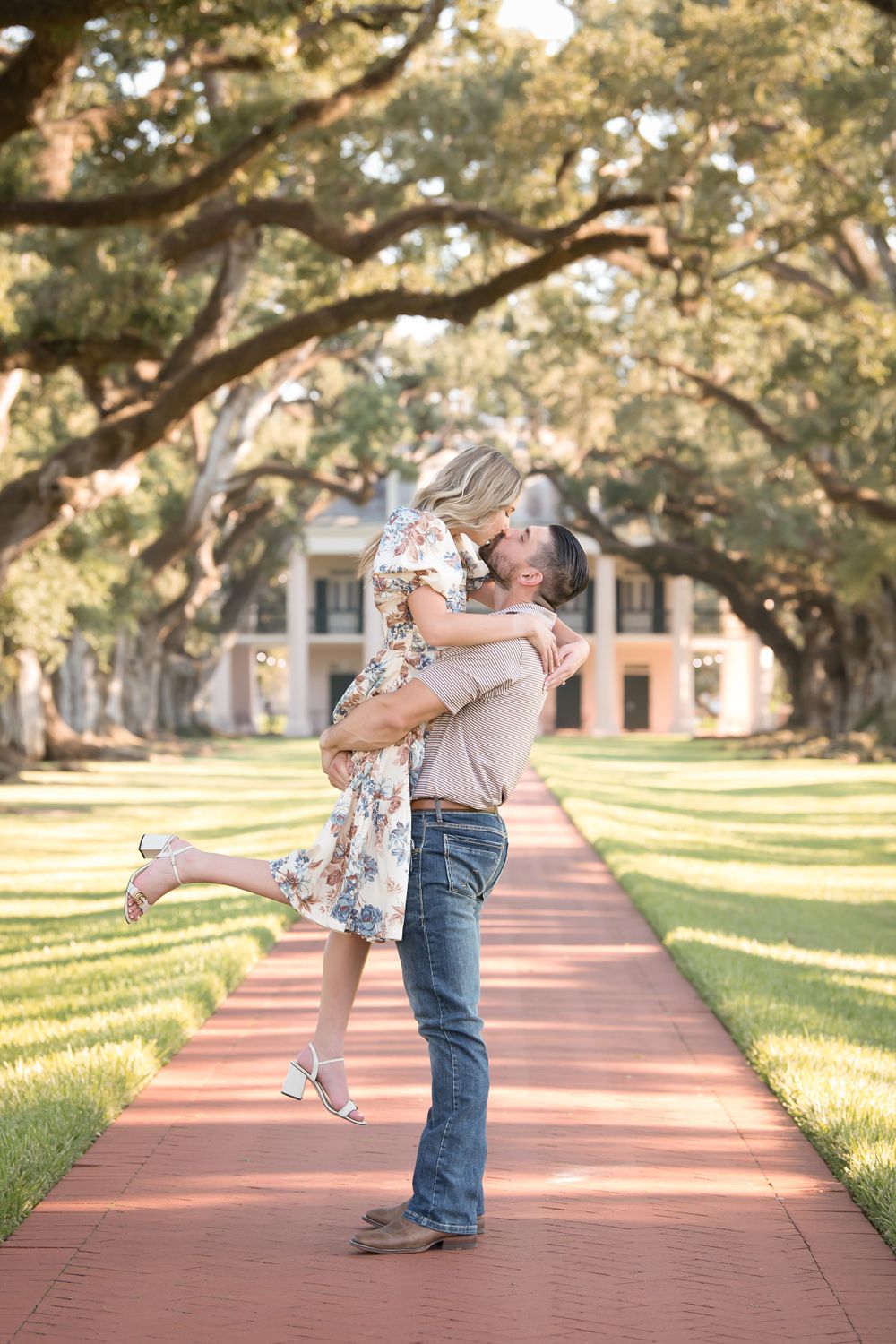 Playful couple photos on a brick pathway with oak trees creating a natural canopy.