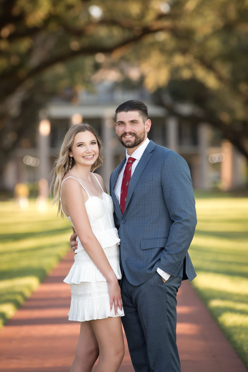 Couple in formal attire shares intimate moments during outdoor engagement photoshoot at sunset.