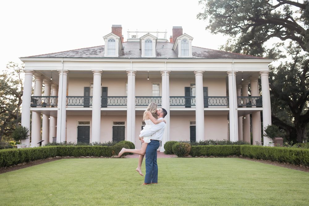 Panoramic view of a white columned antebellum mansion with manicured hedges and lawn.