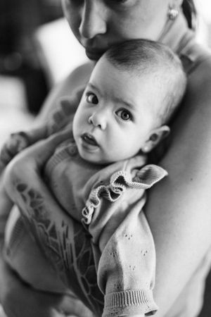 Black and white portrait of baby wearing knit sweater being held.