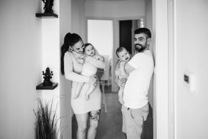 Black and white family portrait of parents holding their babies in a hallway.