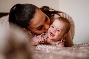 Joyful moment between parent and laughing baby on bed.