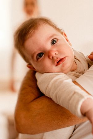 Baby looking up with bright curious eyes while being held.