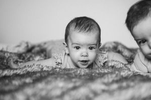 Black and white portrait of baby peeking through textured blanket.