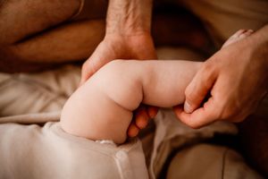 Close-up shot of a baby's chubby legs resting on soft beige fabric.