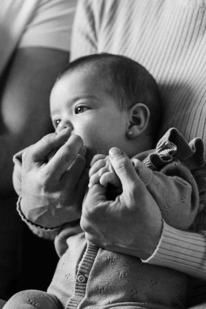 Black and white close-up of a baby's face being gently touched while wearing a knit sweater.