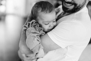 Intimate black and white portrait of nurturing moment as baby rests against shoulder.