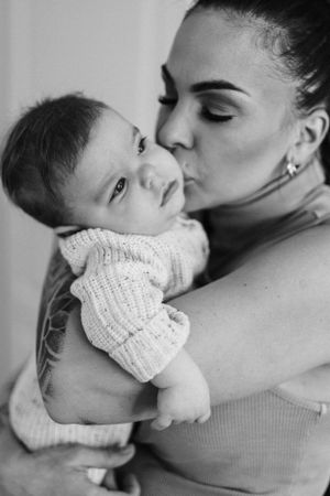 Black and white intimate portrait showing tender moment between caregiver and baby.