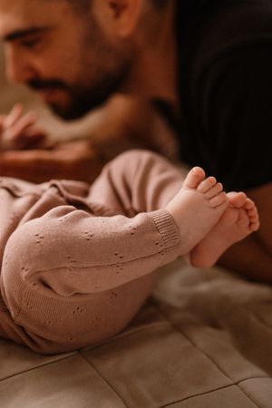 Close up of tiny baby feet in knitted pink clothing with parent in background.