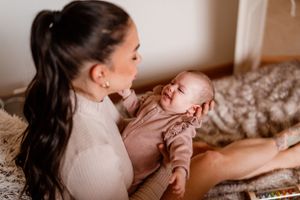 Tender moment between parent and baby on textured bedding.