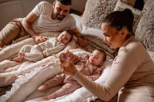 Tender family moment on a bed with parents attending to their babies.