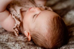 Sleeping infant resting peacefully on a grey furry blanket.