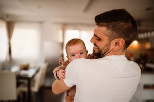 Tender parenting moment captured in warm lighting as baby is held close.