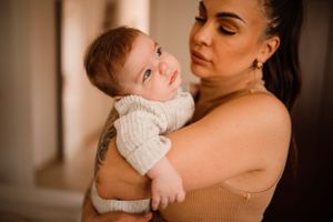 Intimate portrait of nurturing moment with baby in white knit sweater.