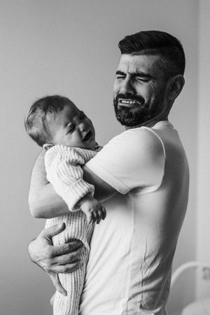 Black and white portrait showing joyful interaction between parent and baby.