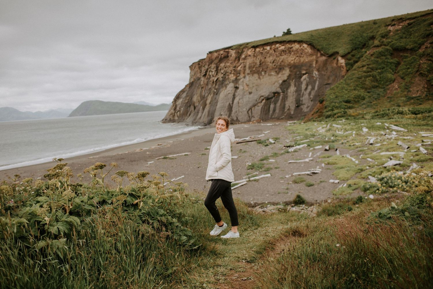 A person walking along a coastal cliff path with dramatic rocky shoreline views.