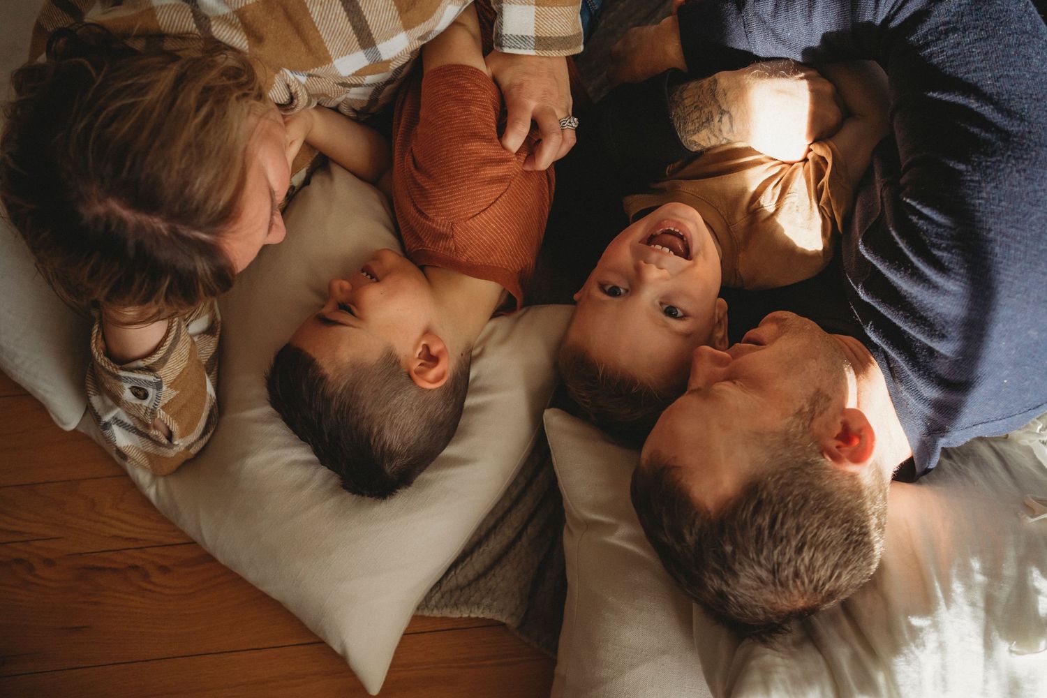Group laying together on floor with heads in circle sharing intimate moment in warm lighting.
