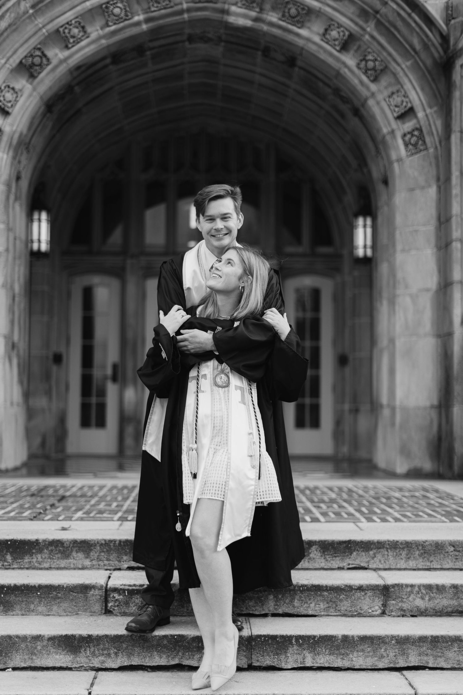 Black and white photos of couple posing playfully on stone steps.