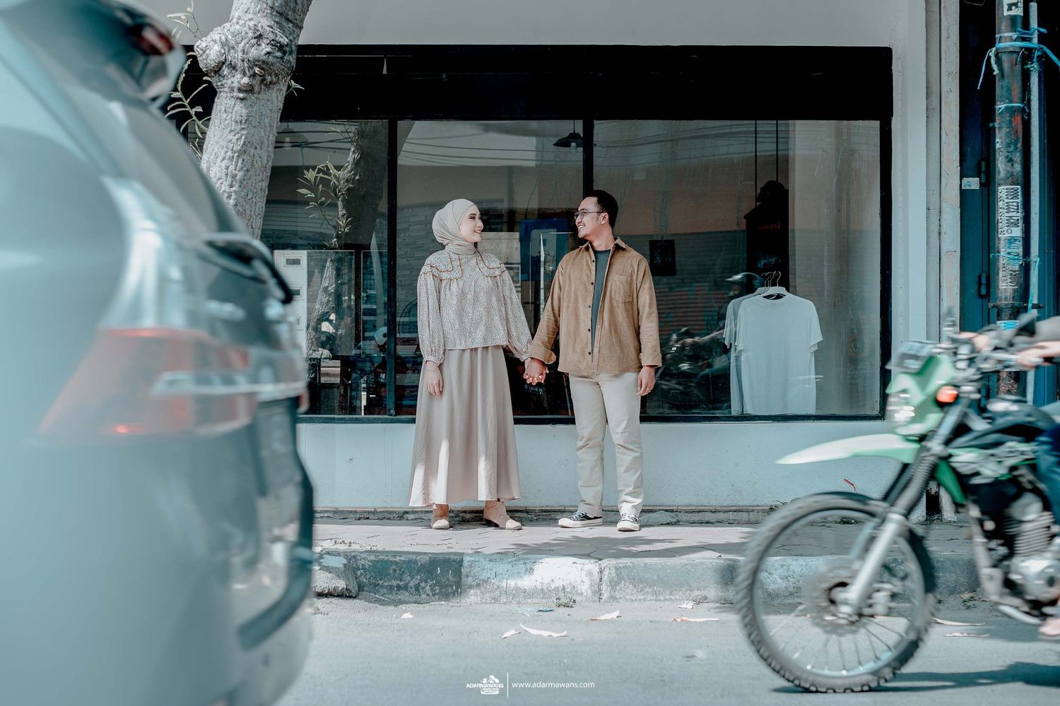 A couple stands outside a modern building with a parked bicycle in the foreground.