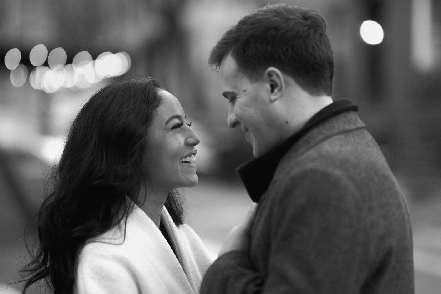 A romantic black and white portrait of a couple sharing an intimate moment on a city street at night.