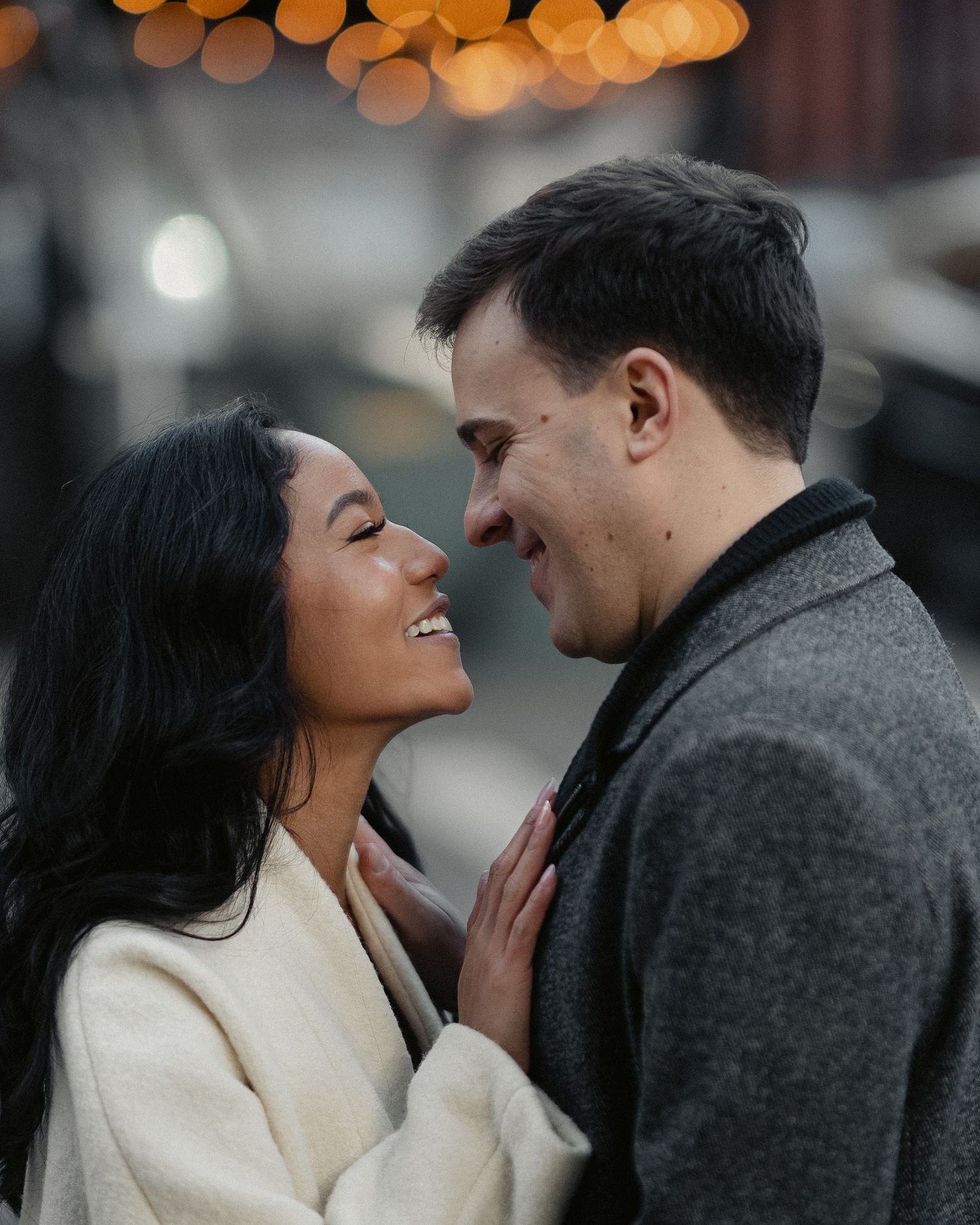 A couple shares a tender moment with warm bokeh lights in the background.