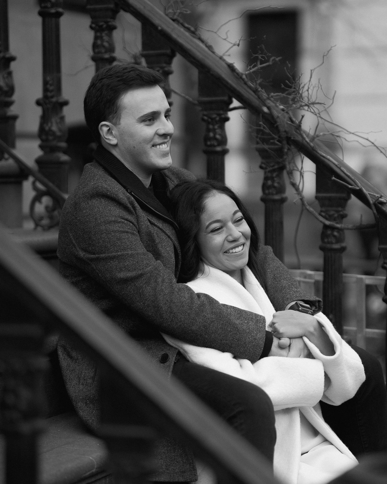 Candid black and white photo of a couple embracing on stone steps.
