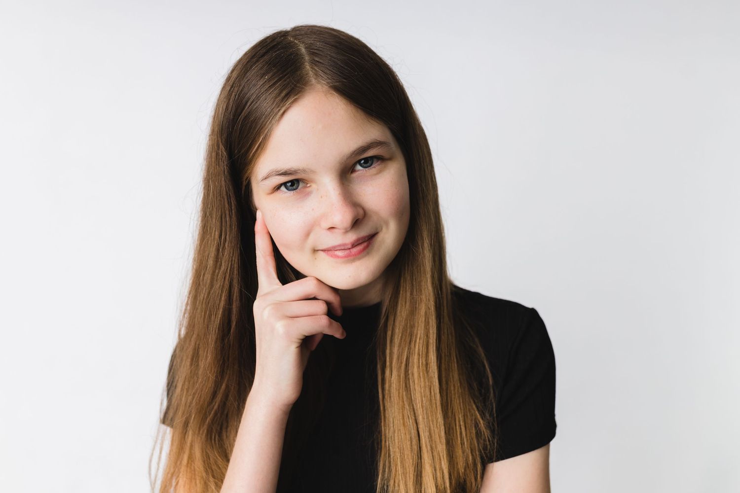 Portrait of a person in black against white background with hand on chin.