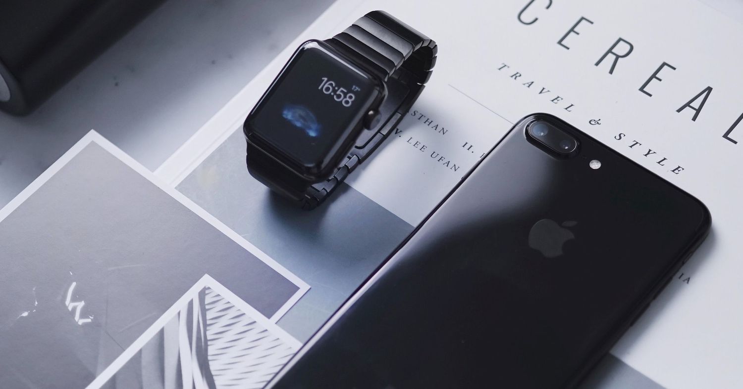 Black iPhone and digital watch displayed on magazine with modern aesthetic.