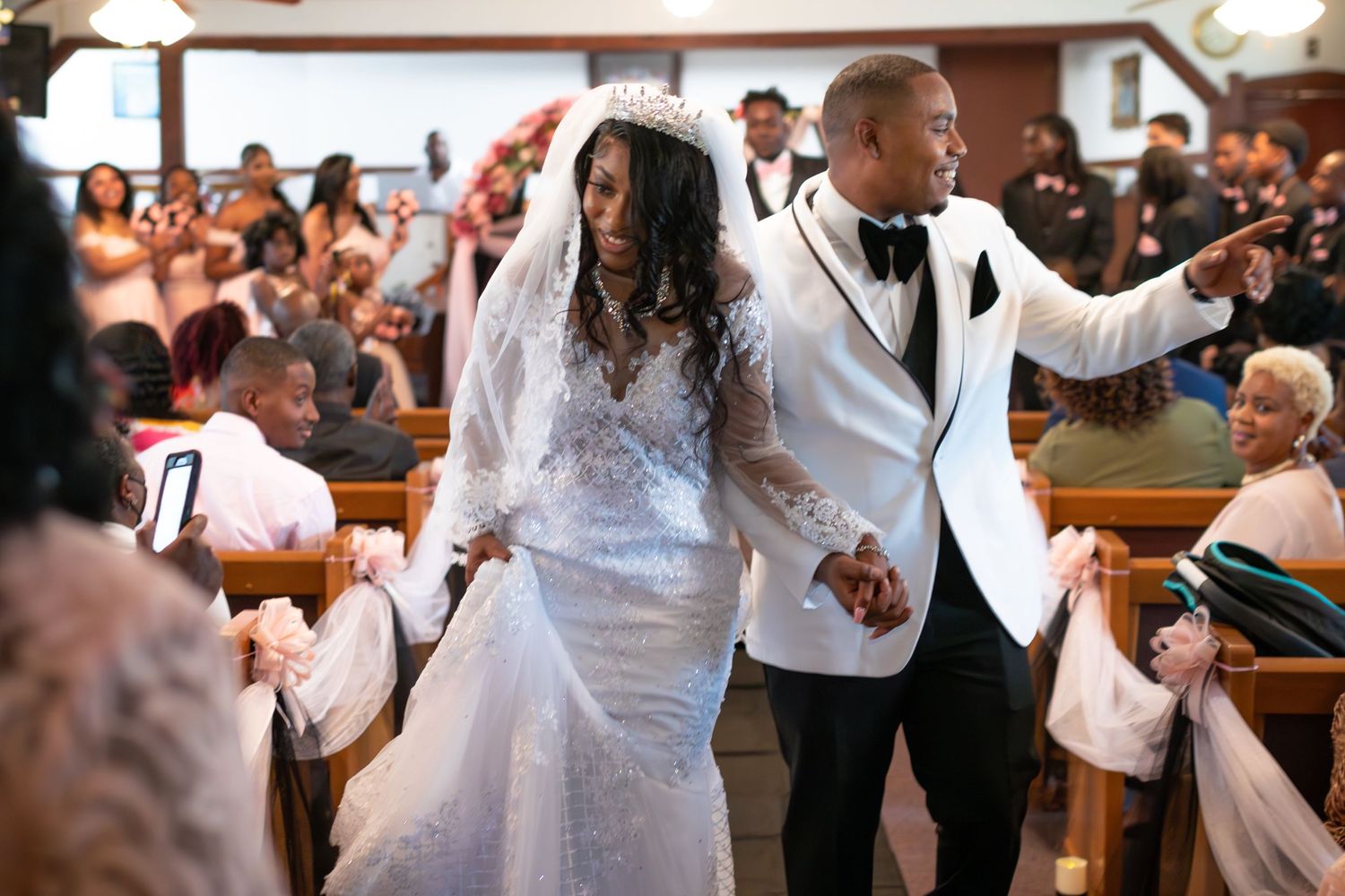 Newlyweds celebrating and dancing in church surrounded by joyful wedding guests.
