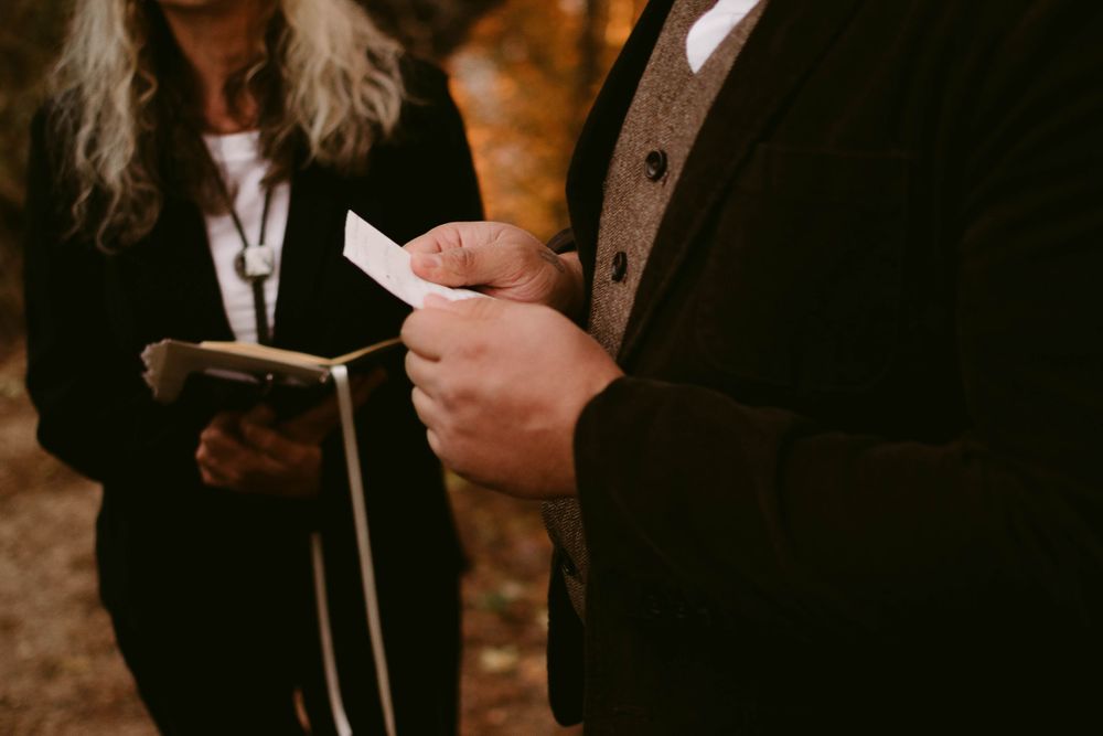 Close-up of hands holding ceremony papers during an outdoor wedding.