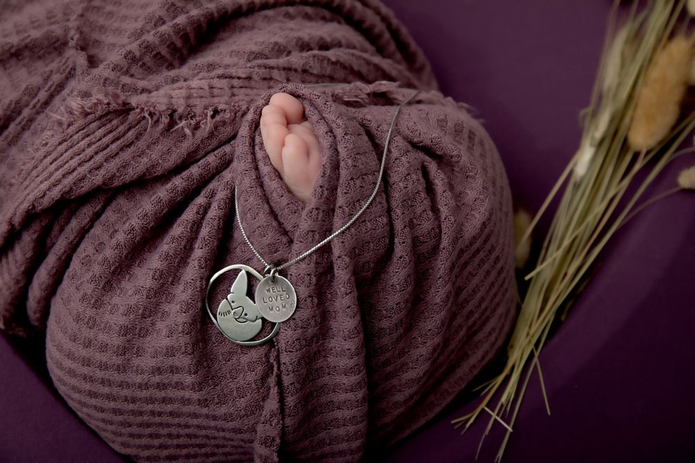 Close up detail of brown knit wrap with silver pendant and dried wheat stalks.